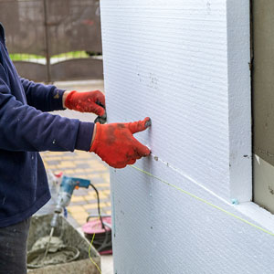 artisan procédant à une isolation thermique par l’extérieur d’un bâtiment, par la pose d’un doublage constitué de panneaux isolants