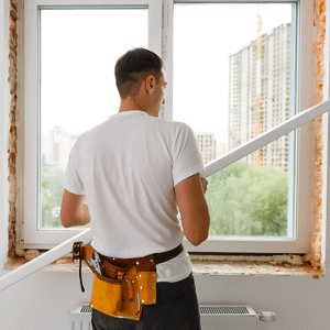 artisan menuisier travaillant sur la pose d’une fenêtre acoustique en rénovation