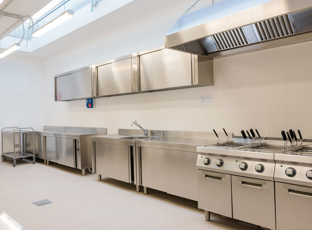 Cuisine industrielle avec hotte aspirante professionnelle dans un espace de restauration collective traité acoustiquement