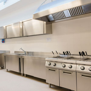 Cuisine industrielle avec hotte aspirante professionnelle dans un espace de restauration collective traité acoustiquement