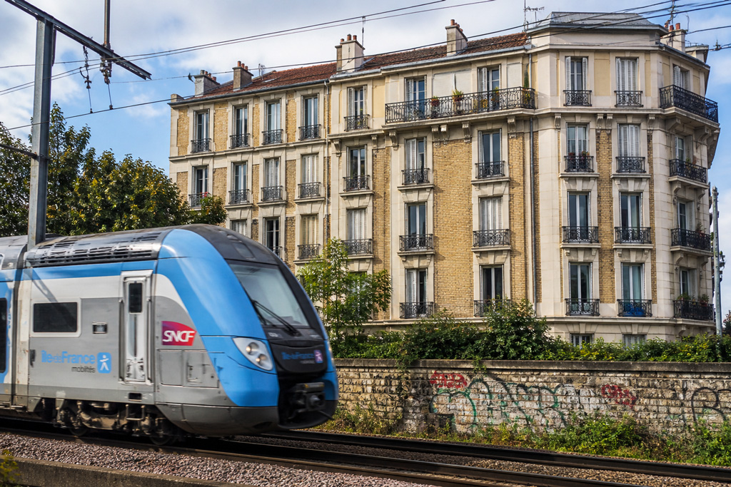 Train SNCF passant devant un immeuble d’habitation en milieu urbain exposé au bruit ferroviaire