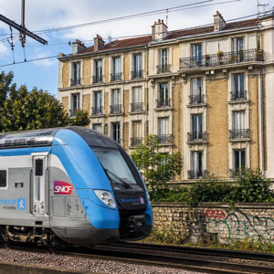 Train SNCF passant devant un immeuble d’habitation en milieu urbain exposé au bruit ferroviaire